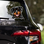 Car window with a Rottweiler sticker of a dog on a blurred outdoor background
