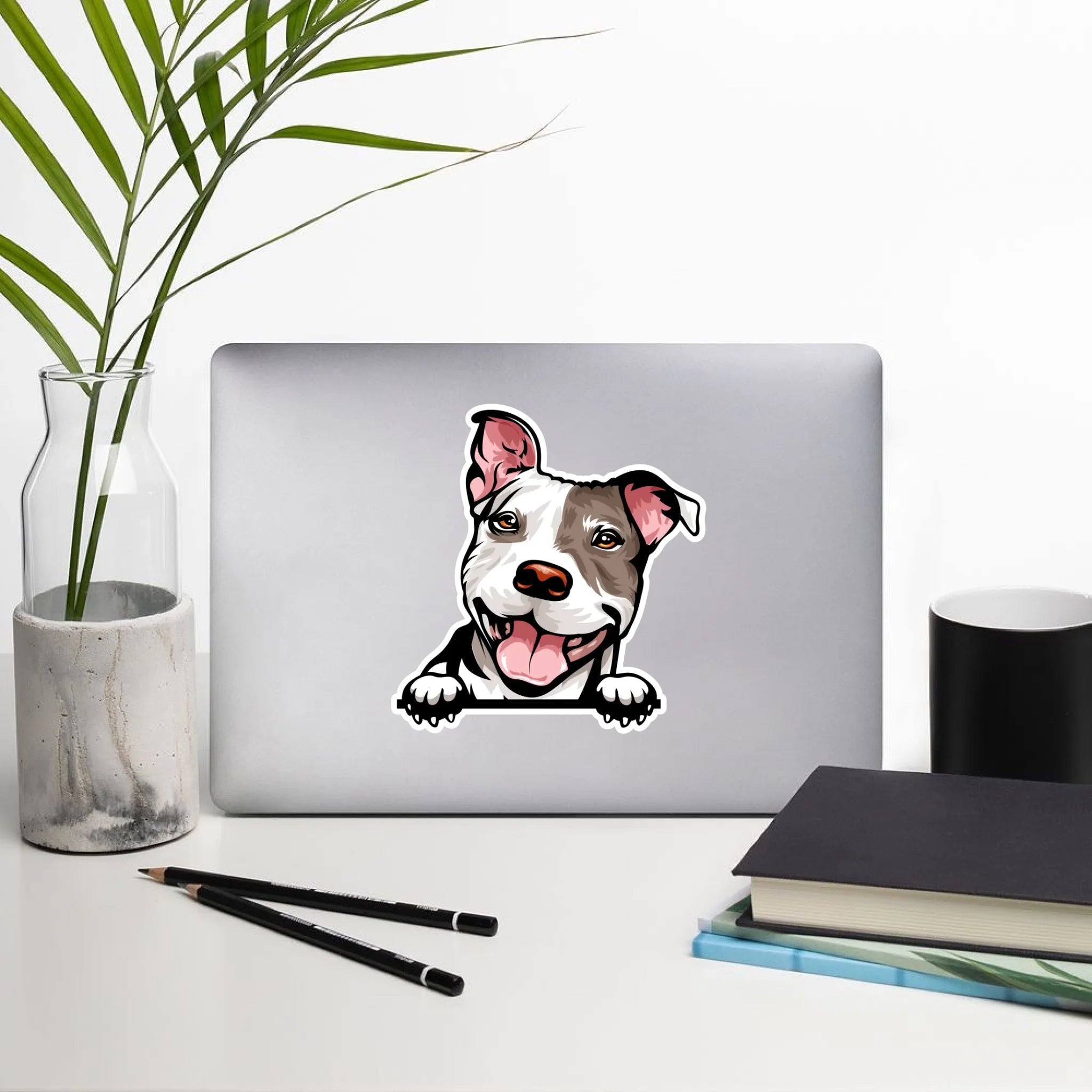 Pit Bull sticker on laptop on a desk with a plant, mug, and books